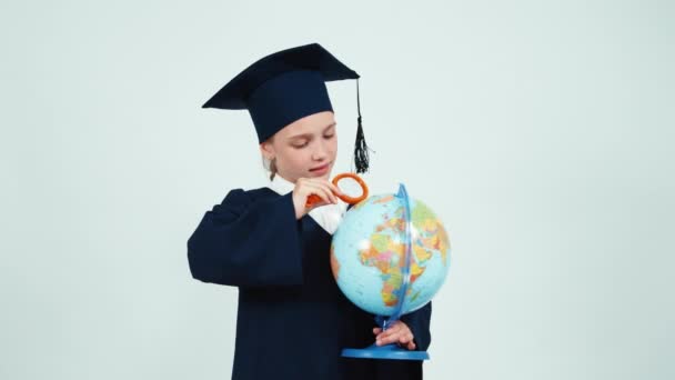 Retrato chica graduada 7-8 años en el manto mirando a través de globo de lupa — Vídeos de Stock