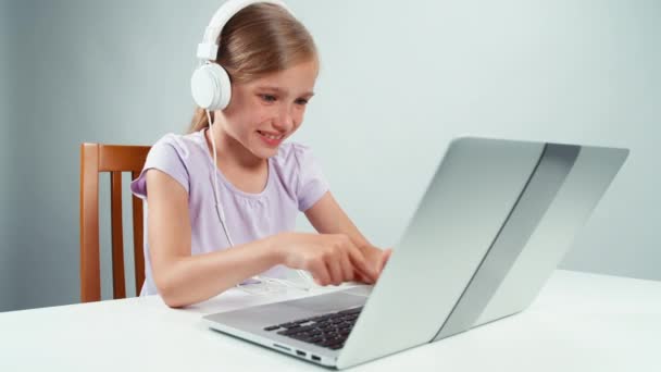 Portrait happy schoolgirl listening music in headphones and something typing in laptop — Stock Video