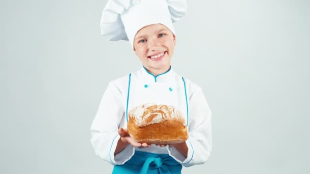 Портрет маленький пекарь держит хлеб в руках и улыбается в камеру изолированы на белом — стоковое видео