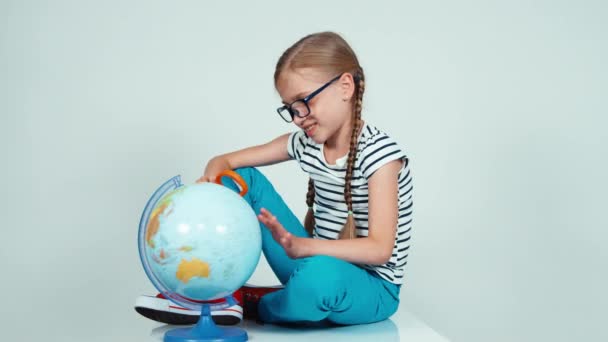 Stående skola flicka spinning hennes globe och tittar kameran isolerad på vit bakgrund — Stockvideo