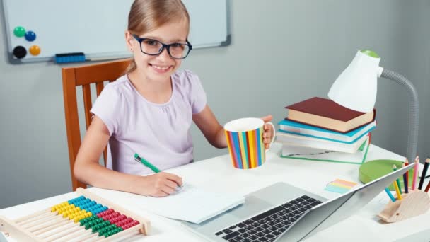Retrato estudante menina 7-8 anos fazendo lição de casa e beber chá de xícara — Vídeo de Stock