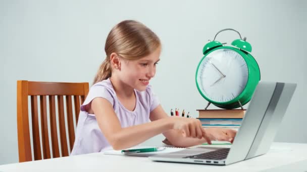 Menina estudante retrato 7-8 anos algo digitando no laptop e se alegrando e olhando para a câmera. Mãos para cima. Criança tem surpresa — Vídeo de Stock