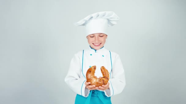 Retrato joven panadero parte pan bagel le da una pieza en la cámara y sonriendo aislado sobre fondo blanco — Vídeos de Stock