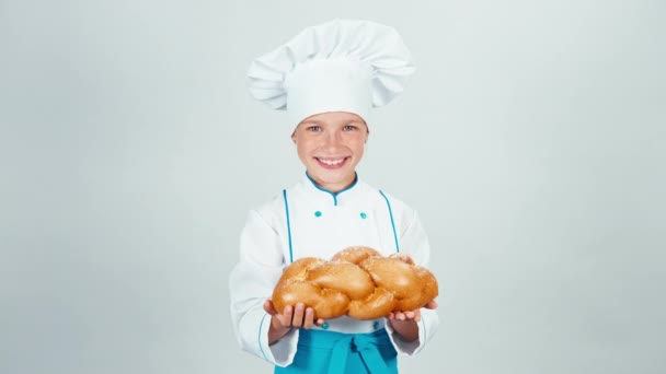 Портрет молодой пекарь держит большой плетеный хлеб и дает буханку вам на камеру и улыбаясь изолированы на белом фоне — стоковое видео