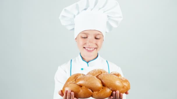 Portret jonge baker bezit gevlochten brood en brood dat je op de camera en glimlachend geïsoleerd op een witte achtergrond geeft — Stockvideo