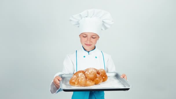 Portret jonge baker houdt oven-tray met gevlochten brood en brood dat je op de camera en glimlachend geïsoleerd op een witte achtergrond geeft — Stockvideo