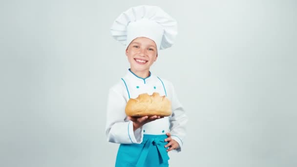 Retrato jovem padeiro segura pão redondo em suas mãos e dá-lhe pão e sorrindo para a câmera isolada no fundo branco — Vídeo de Stock