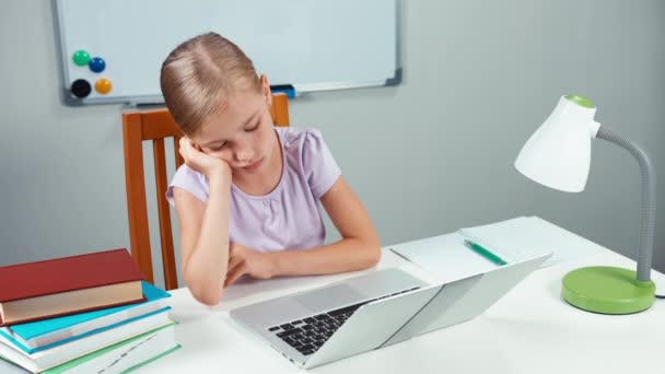 Грустная девочка 7-8 лет с ноутбуком сидит в столе и смотрит в камеру. Вид сверху — стоковое видео