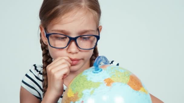 School meisje 7-8 jaar iets zoeken op haar wereldbol en lachend op camera — Stockvideo