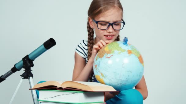 School girl 7-8 years something searching on her globe and with surprised looking at camera — Stock Video