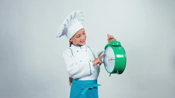 Boos chef-kok koken kind 7-8 jaar houden wekker en permanent geïsoleerd op witte achtergrond — Stockvideo