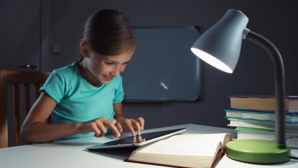 Sehr fröhliches Mädchen Kind 7-8 Jahre alt mit Tablet in der Nacht auf ihrem Schreibtisch und lacht in die Kamera. Daumen hoch. ok — Stockvideo