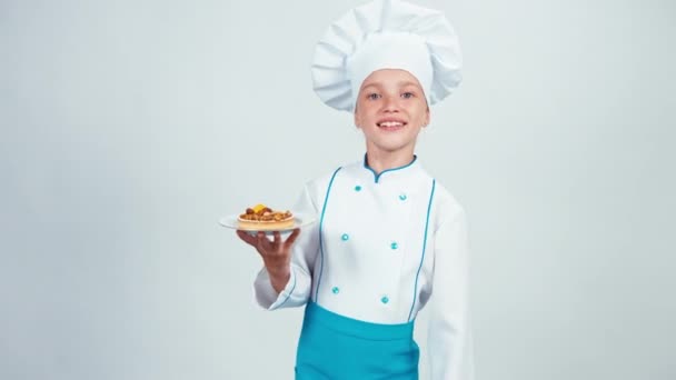 Νεαρό φούρναρη εισέρχεται το πλαίσιο κατέχει μικρό κέικ με ξηρούς καρπούς και δίνει σας να στέκεται απομονωθεί σε λευκό — Αρχείο Βίντεο