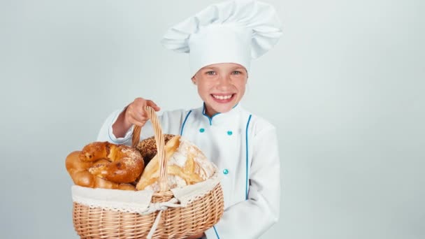 Молодой пекарь держит корзину с хлебом и улыбается в камеру на белом фоне — стоковое видео