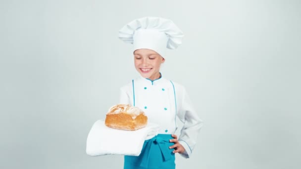 Joven panadera sostiene el pan en sus manos y sonríe a la cámara aislada sobre fondo blanco — Vídeos de Stock