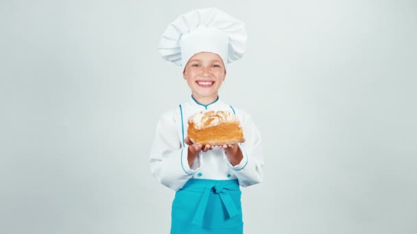 Młody piekarz trzyma chleb w jej ręce i wąchania to i zapewnia i uśmiecha się do kamery na białym tle — Wideo stockowe