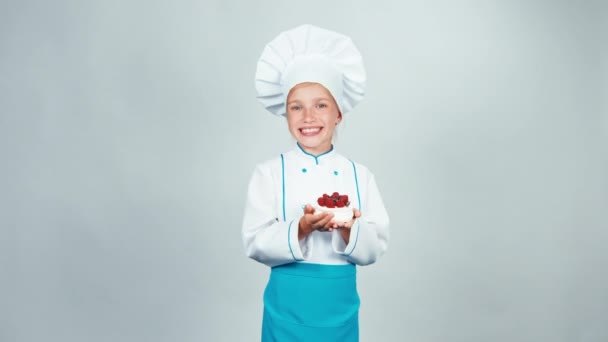 Die junge Bäckerin hält Baiser-Kuchen in der Hand und reicht ihn lächelnd in die Kamera. isoliert auf weiß — Stockvideo