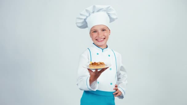 Giovane panettiere tiene piatto con piccola torta con noci in piedi isolato su bianco. Pollice in alto. Va bene. — Video Stock