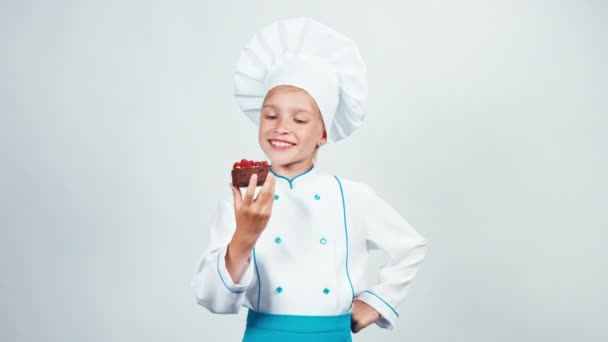 Jeune boulanger reniflant gâteau au chocolat avec des framboises et vous le donne. Chef souriant à la caméra. Isolé sur blanc. Levez le pouce. D'accord. — Video