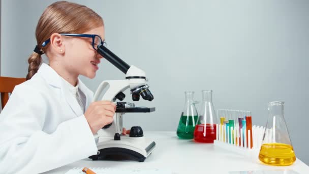 Νεαρός χημικός κορίτσι χρησιμοποιώντας μικροσκόπιο και να χαμογελά στη φωτογραφική μηχανή — Αρχείο Βίντεο