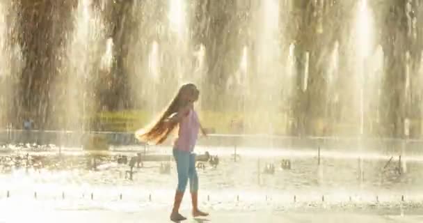 Девочка кружится на фоне фонтана — стоковое видео