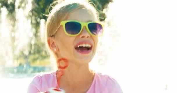 Close-up van portret meisje blazen van zeepbellen in de buurt van fontein en lachen — Stockvideo