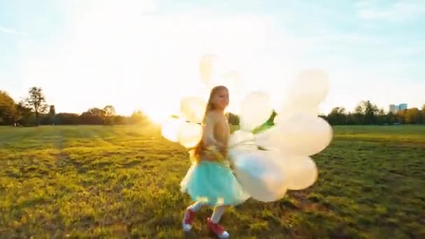 Menina feliz criança 8-9 anos de idade correndo através do campo e girando com seus balões brancos no pôr do sol — Vídeo de Stock