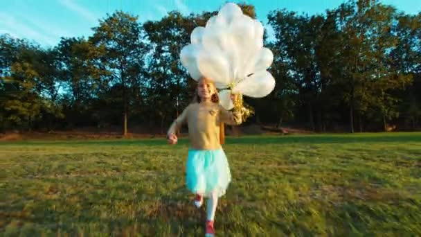 Kind 8-9 jaar oud draait op camera en houdt haar witte ballonnen en glimlachen — Stockvideo