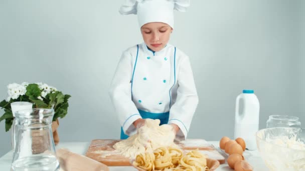 Young baker girl making dough at the kitchen table isolated on white — Stock Video