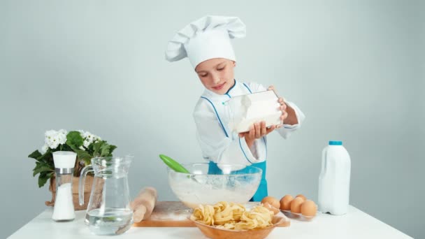 Cook lägger mjölet i degen och använda kök visp och ler mot kameran — Stockvideo