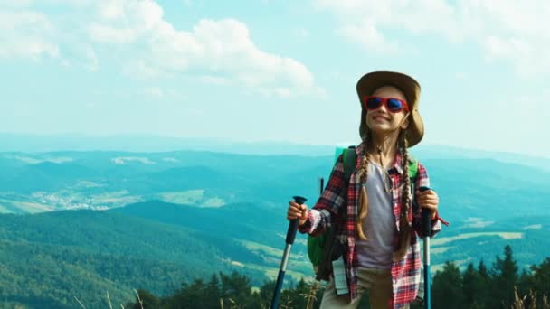 Πορτρέτο τουριστικά κορίτσι παιδί με Σακίδια 7-8 χρόνια ενάντια στα βουνά που βλέπουν τα φωτογραφικών μηχανών — Αρχείο Βίντεο
