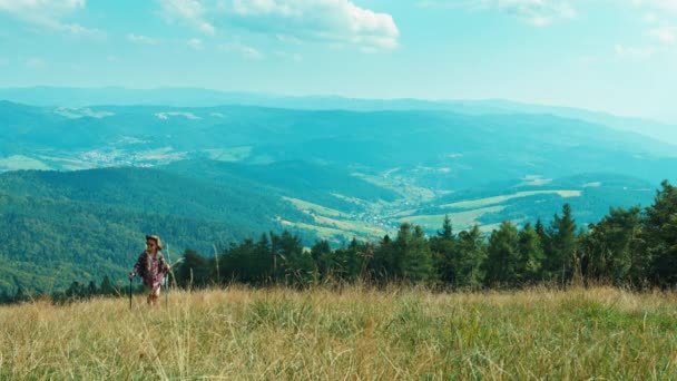 Little hiker girl going up the hill on mountains background at camera — Stock Video