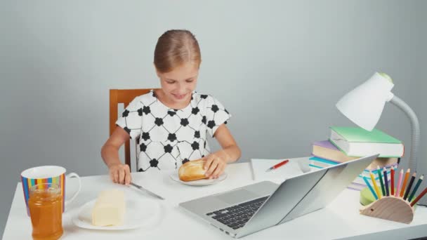 Schulmädchen macht Sandwich mit Butter am Schreibtisch sitzend und abends lächelnd — Stockvideo