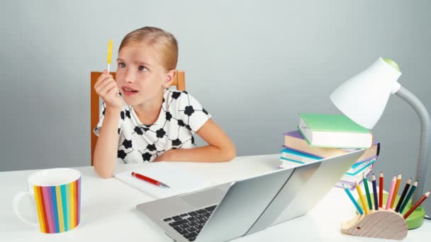 Schoolgirl looking at her lollipop and smiling at camera sitting at the desk in the evening. Thumb up. Ok — Stock Video