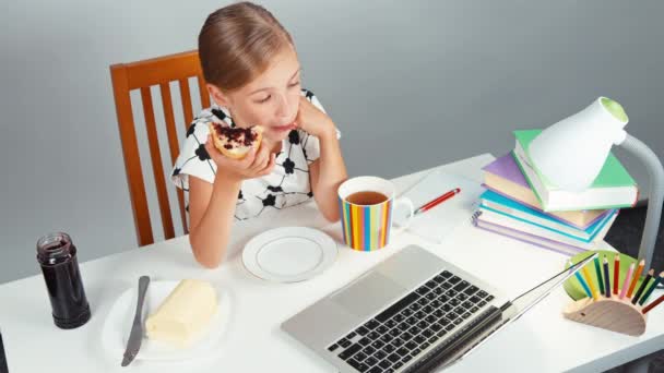 Schulmädchen 7-8 Jahre essen Sandwich mit Butter und Marmelade und sitzen abends am Schreibtisch. Daumen hoch. ok. von oben — Stockvideo