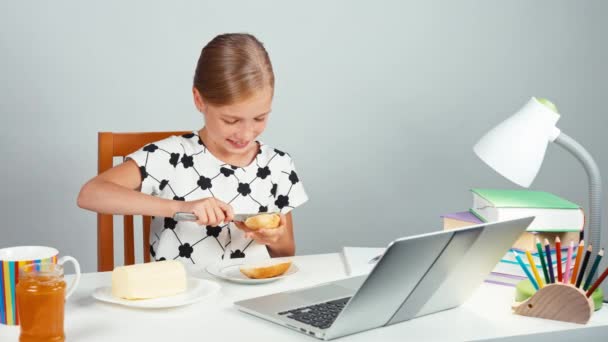 Portret school meisje 7-8 jaar maken van sandwich met boter en jam zitten aan de balie in de avond — Stockvideo