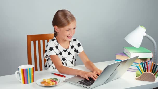 Girl 7-8 years using laptop and eating marmalade candy. Child doing homework at home. Thumb up. Ok — Stock Video