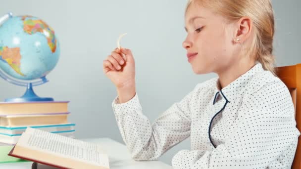 Studentessa mangiare patatine fritte e leggere il libro di testo e leccare le dita sporche — Video Stock