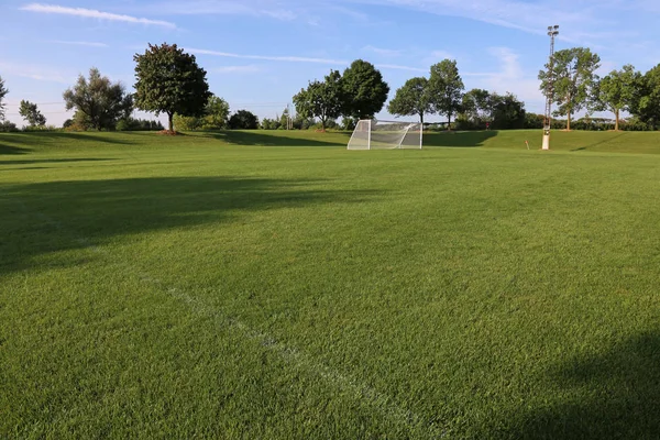 A view of a net on a vacant soccer pitch in morning light