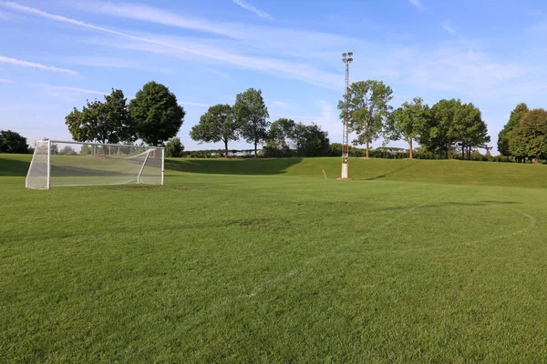 A view of a net on a vacant soccer pitch in morning light