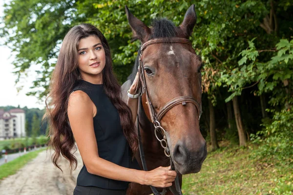 Ganska ung kvinna och en brun häst Stockfoto