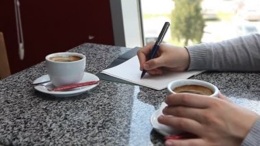 Kahve içme ve bir şey kafede iş planlayıcısındaki yazma kadın