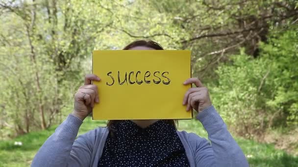 Jonge Vrouw Met Een Gele Stuk Papier Met Succes Handgeschreven — Stockvideo