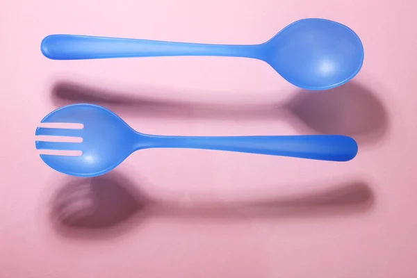 粉色背景下的塑料叉子和勺子 — 图库照片