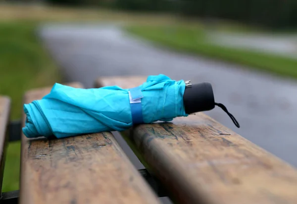 Guarda-chuva dobrado em um banco — Fotografia de Stock