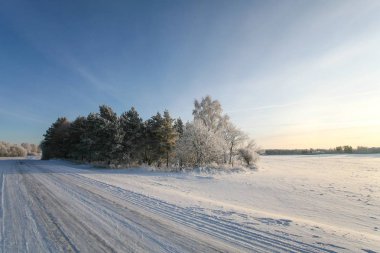 Karlı ve buzlu, boş kırsal kış yol gün batımında