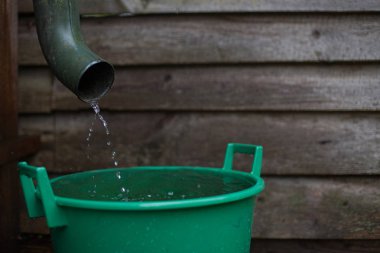 Rainwater shooting from a gutter into a water collecting reservoir clipart