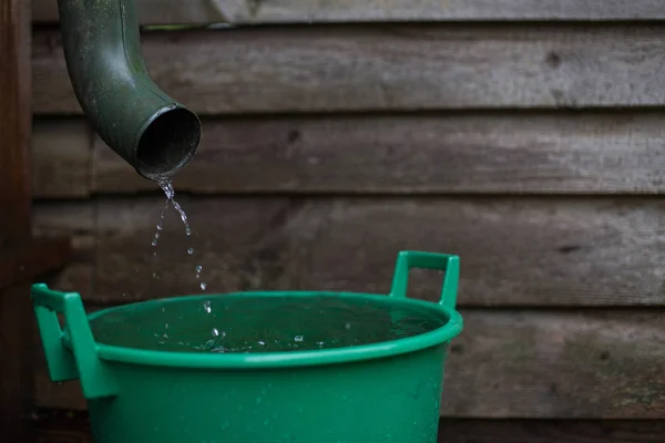 Regenwasser schießt aus einer Regenrinne in ein Auffangbecken — Stockfoto