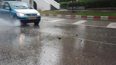 Yolda su birikintisinden su sıçrayan bir araba.