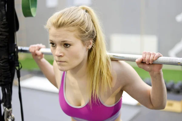 Vrouw tillen gewichten in gym — Stockfoto